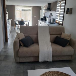 a living room with a couch and a kitchen at Gîte LA FONTAINE DU MARAIS in Pendé