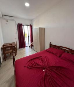 a bedroom with a bed with a red bedspread at Sar Hotel, Velipojë in Velipojë