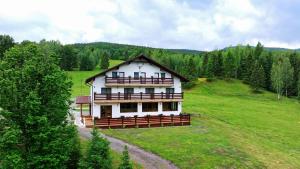 a large white house in a field with trees at Belvedere Retezat in Cîmpu lui Neag
