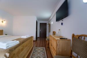 a bedroom with a bed and a television on the wall at Belvedere Retezat in Cîmpu lui Neag