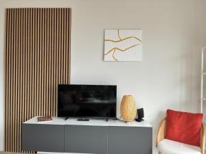 a living room with a television on a cabinet and a chair at Riviera Feeling - Ospedaletti in Ospedaletti