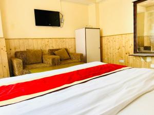a room with a bed and a tv and a couch at Regency Shooryaa Near The Mall Shimla in Shimla