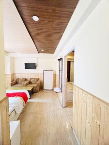 a room with two beds and a couch and a tv at Regency Shooryaa Near The Mall Shimla in Shimla