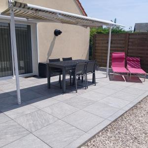 a black table and two pink chairs on a patio at Gîte LA FONTAINE DU MARAIS in Pendé +2 photos