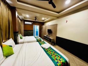 a hotel room with two beds and a television at Satkar Comforts in Attigundi