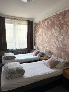 a hotel room with three beds and a stone wall at Hotel Wandsbek Hamburg in Hamburg
