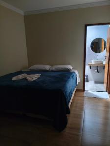a bedroom with a bed and a bathroom with a sink at Felício Reis - Pousada Colonial in Conceição do Mato Dentro