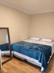a bedroom with a bed with blue sheets and a mirror at Felício Reis - Pousada Colonial in Conceição do Mato Dentro