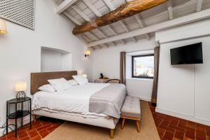 a bedroom with a bed and a flat screen tv at Quarto Duplo - Pacote Alentejo 3 Noites in Alcáçovas