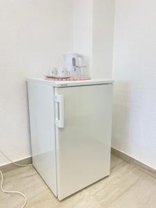 a small white refrigerator with two cups on top of it at Dora Apartman in Tomislavgrad +5 photos