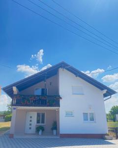 a white house with a balcony on the side at Dora Apartman in Tomislavgrad