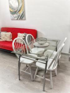 a glass table and chairs with a red couch at Rentdragoana in Costa Del Silencio