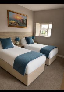 two beds in a hotel room with two windows at Grove house Dunleer in Dún Léire