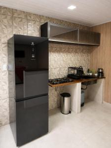 a kitchen with a black refrigerator and a counter at Mini Casa Privativa -Praia do Tombo in Guarujá