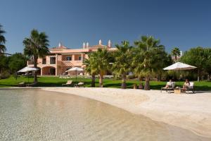 two people sitting on chairs on the beach in front of a house at Cascade Wellness Resort Lagos Algarve by Domes in Lagos