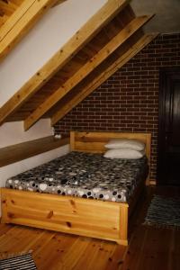a wooden bed in a room with a brick wall at Casa de Piatra in Porumbacu de Sus