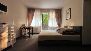 a bedroom with a bed and a desk and a window at Villa Góralka in Polanica-Zdrój