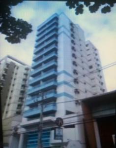 a tall white building with blue windows at Apart Quartier Latin Hotel in Vitória