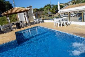 a blue swimming pool with chairs and a gazebo at Prime Garden Pousada in Socorro +17 photos