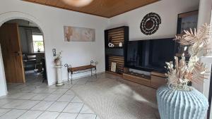 a living room with a large television and a vase with a plant at Auszeit Eifel Ihre private Auszeit zu zweit in Reuth
