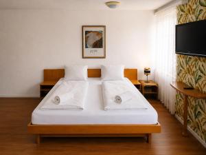 a bedroom with a bed with white sheets and a flat screen tv at KB CityRooms Self-Check-In in Lucerne