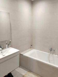 a white bathroom with a tub and a sink at Résidence Costa in Sousse