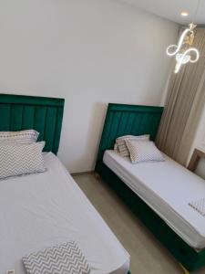 two beds with green headboards in a room at Résidence Costa in Sousse