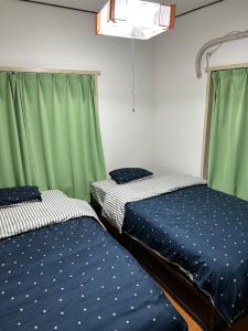 two beds in a room with green curtains at 馨誠小屋201 in Tokyo