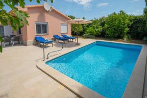 a swimming pool with chairs and an umbrella at House Nada 1201 in Banjole