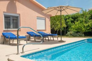 a swimming pool with chairs and an umbrella next to a swimming pool at House Nada 1201 in Banjole