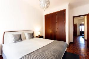 リスボンにあるWHome | Damasceno Large Apartment #39の白いベッドと木製キャビネット付きのベッドルーム1室が備わります。