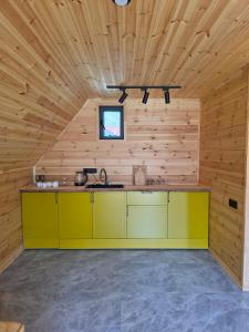 a kitchen with yellow cabinets in a wooden cabin at Кольсай Тау Оректы resort in Kurmenty +19 photos