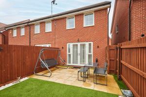 a patio with two chairs and a table in front of a brick building at Host & Stay - Fells Paddock in Bedford