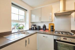 a kitchen with white cabinets and a sink and a window at Host & Stay - Fells Paddock in Bedford