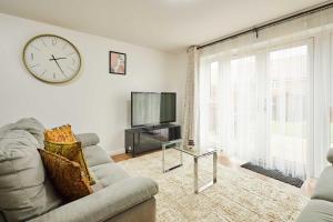 a living room with a couch and a tv and a clock at Host & Stay - Fells Paddock in Bedford