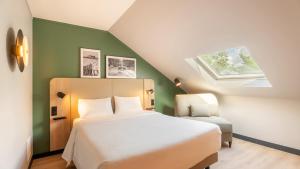 a bedroom with a large white bed and a chair at Campanile NATURE - Vannes in Vannes