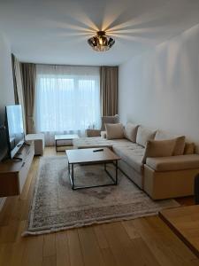 a living room with a couch and a tv at Modern Riverside Apartment in Sarajevo