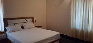 a bedroom with a white bed with a window at Smiley Homestay in Varkala