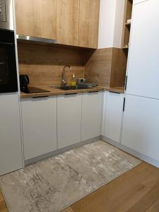 a kitchen with white cabinets and a sink at Modern Riverside Apartment in Sarajevo