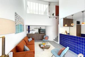 a living room with an orange couch and a kitchen at Temps des Cerises - Terrasse - Plage - Marina in Deauville +25 photos