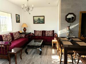 a living room with a red couch and a table at Ferme Sacrée Nature in Ben Slimane