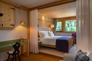 a bedroom with a bed and a desk and a window at Vila Planinka Boutique Hotel in Zgornje Jezersko