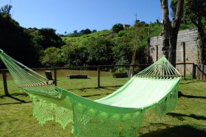 a green hammock in a yard with a field at Prime Garden Pousada in Socorro
