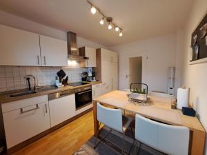 a kitchen with a wooden table and white cabinets at Freds Ferienwohnung in Kelheim