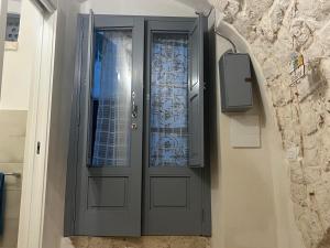 a gray door with a window on a wall at La casetta di Franci in Castellana Grotte