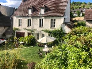 a woman sitting under an umbrella in the yard of a house at La chambre de la grenouille in Giverny