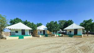 a group of buildings with white roofs on a dirt field at Quba Desert Camp Jaisalmer in Jaisalmer