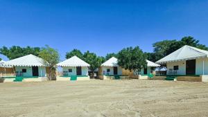 a row of buildings with white roofs and trees at Quba Desert Camp Jaisalmer in Jaisalmer