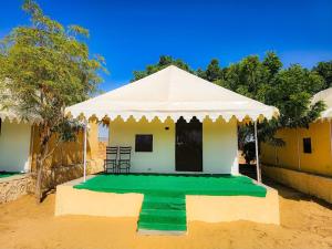 a small house with a green floor and a white tent at Quba Desert Camp Jaisalmer in Jaisalmer +6 photos