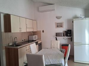 a small kitchen with a table and a white refrigerator at Maison Laujo en bord de mer in Santa-Maria-Poggio